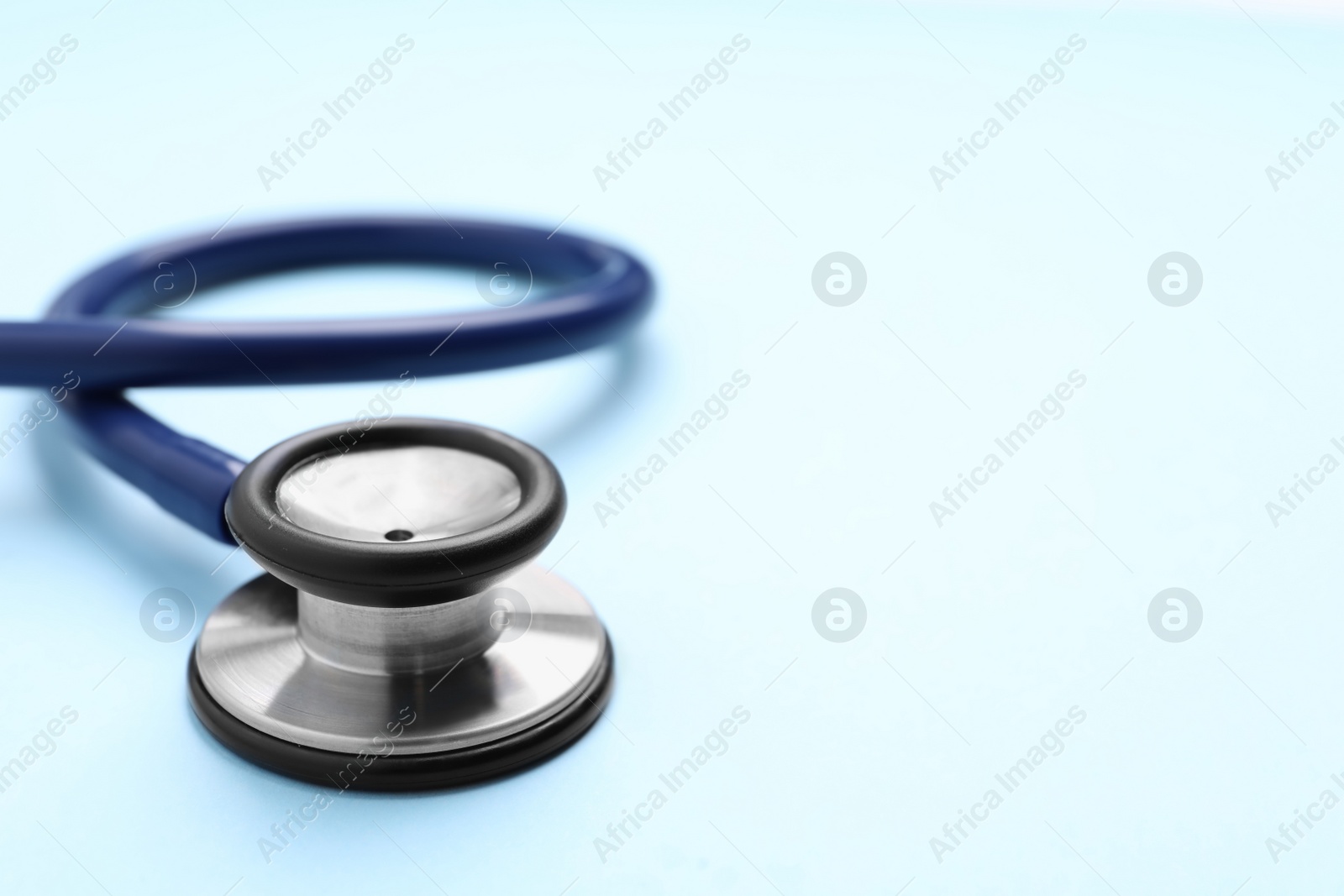 Photo of Stethoscope on light blue background, closeup. Space for text