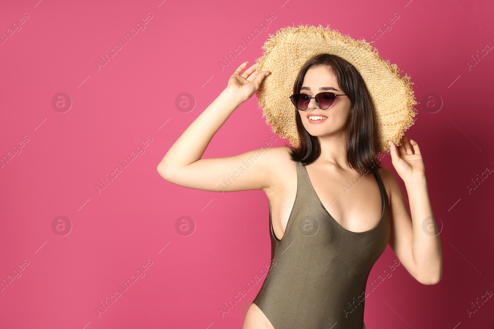 Photo of Beautiful young woman wearing swimsuit, hat and sunglasses on pink background