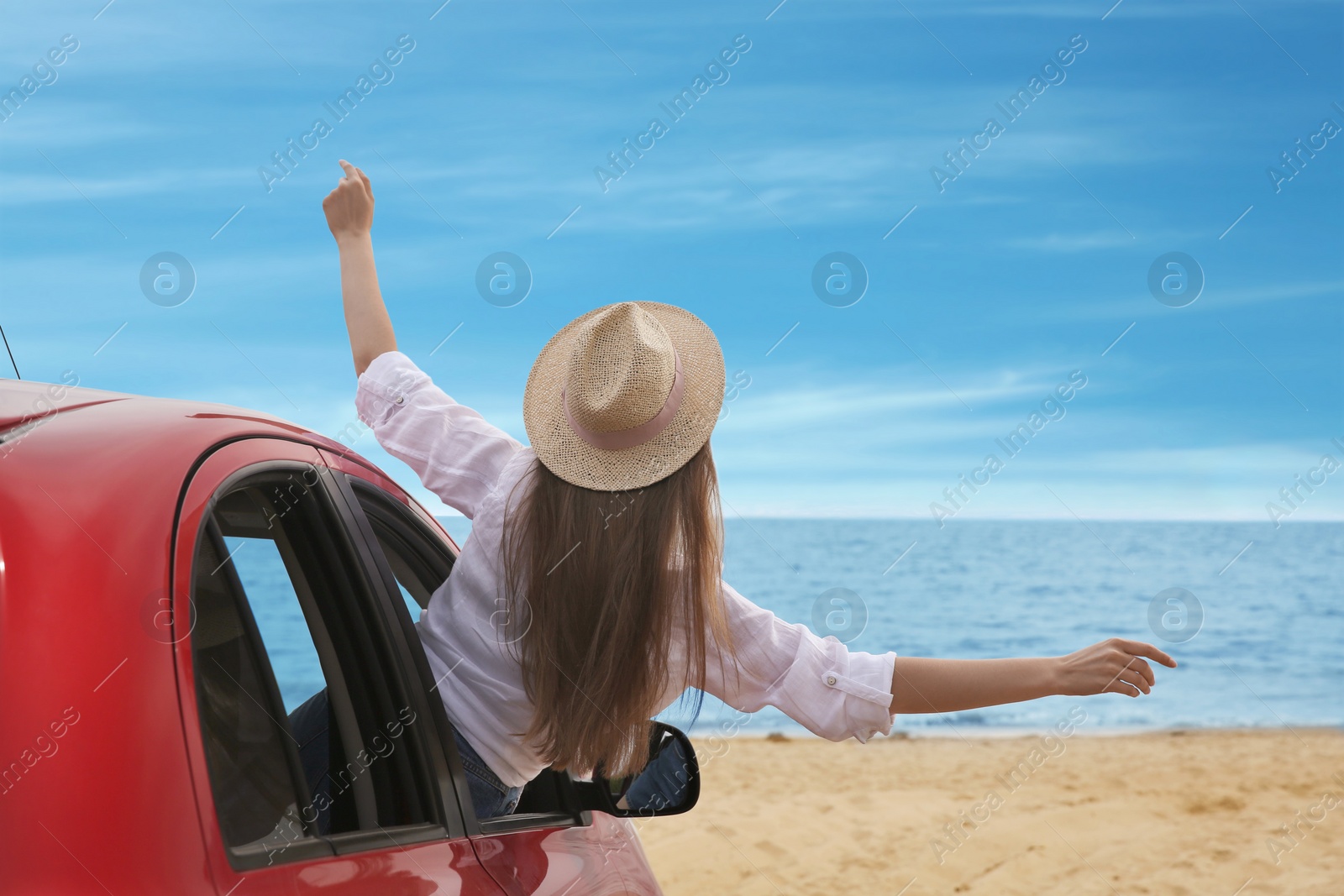 Photo of Happy woman leaning out of car window on beach. Summer vacation trip