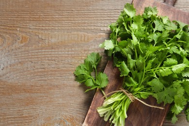 Bunch of fresh aromatic cilantro on wooden table, top view. Space for text