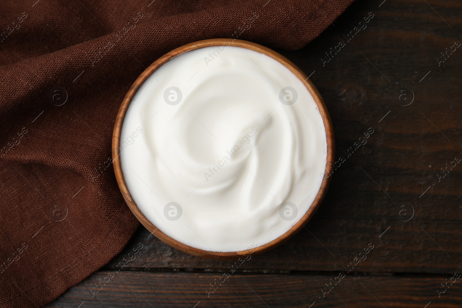 Photo of Delicious natural yogurt in bowl on wooden table, top view