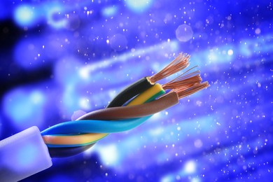 Image of Colorful electrical wires against blue background with blurred lights, closeup. Bokeh effect