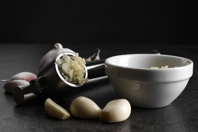 Photo of Garlic press, cloves and mince on grey table, closeup