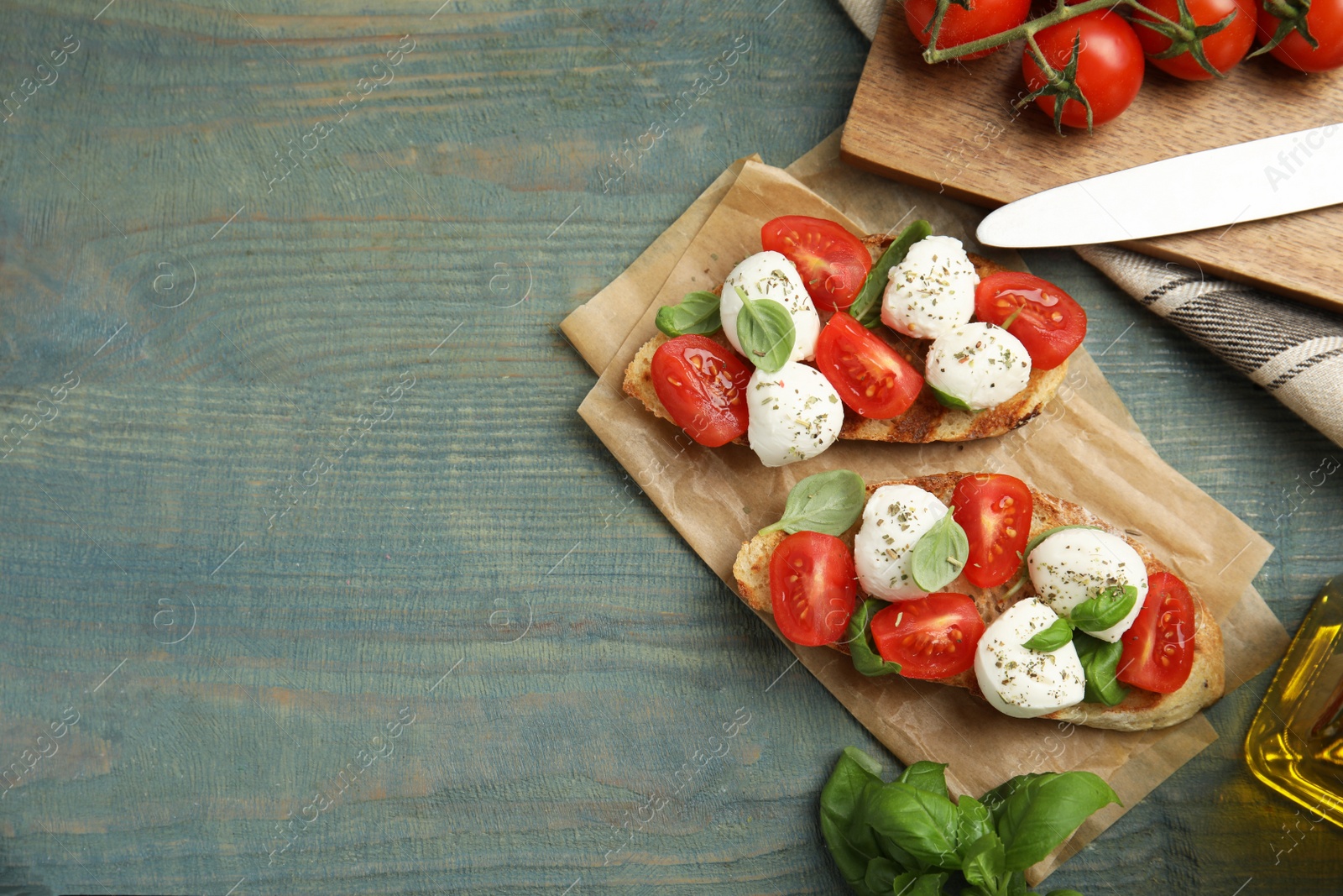 Photo of Delicious sandwiches with mozzarella, fresh tomatoes and basil on blue wooden table, flat lay. Space for text