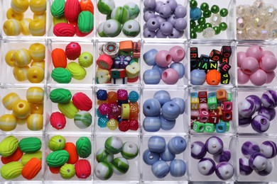 Photo of Plastic organizer with different beads as background, top view