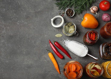 Photo of Flat lay composition with products and jars of pickled vegetables on grey table. Space for text