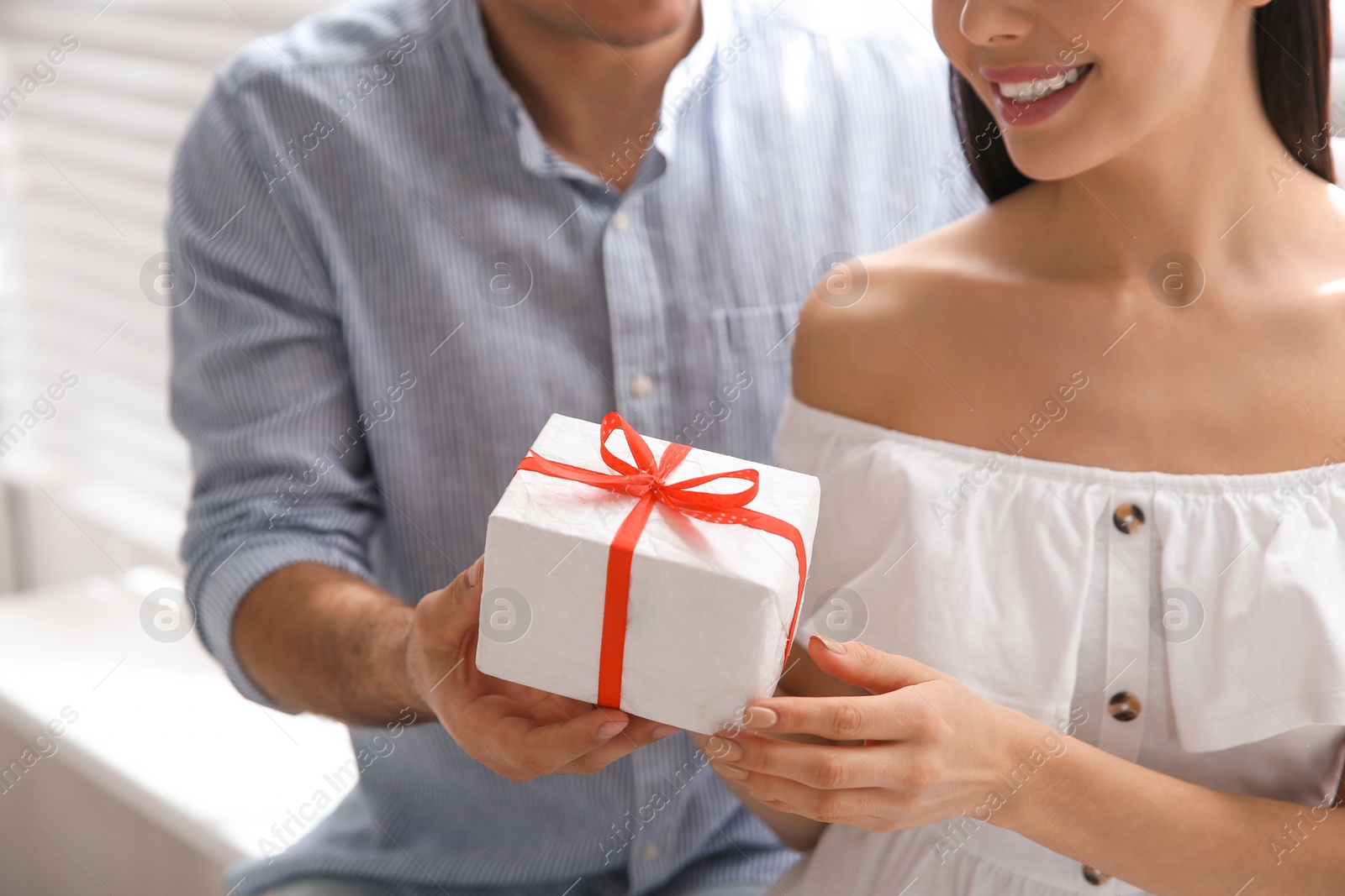 Photo of Man presenting gift to his beloved woman at home, closeup. Valentine's day celebration