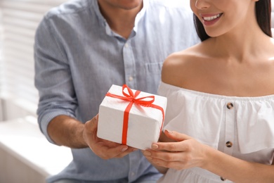 Man presenting gift to his beloved woman at home, closeup. Valentine's day celebration