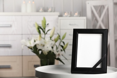 Photo of Funeral photo frame with black ribbon on table, indoors