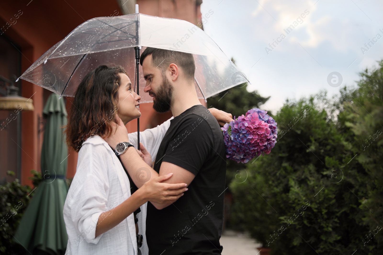 Photo of Young couple with umbrella enjoying time together under rain on city street, space for text