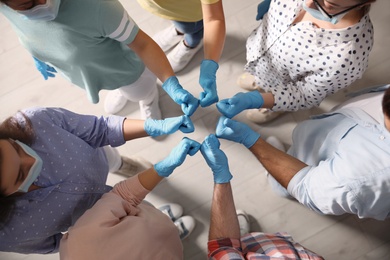 Photo of Group of people in blue medical gloves showing thumbs up indoors, top view