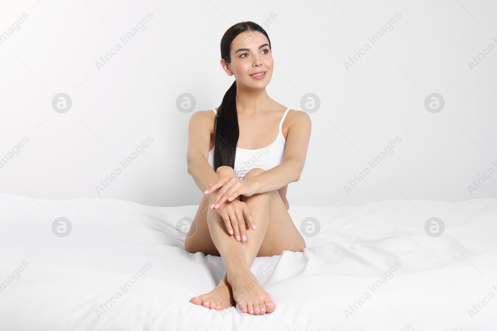 Photo of Young woman showing smooth skin after epilation on bed