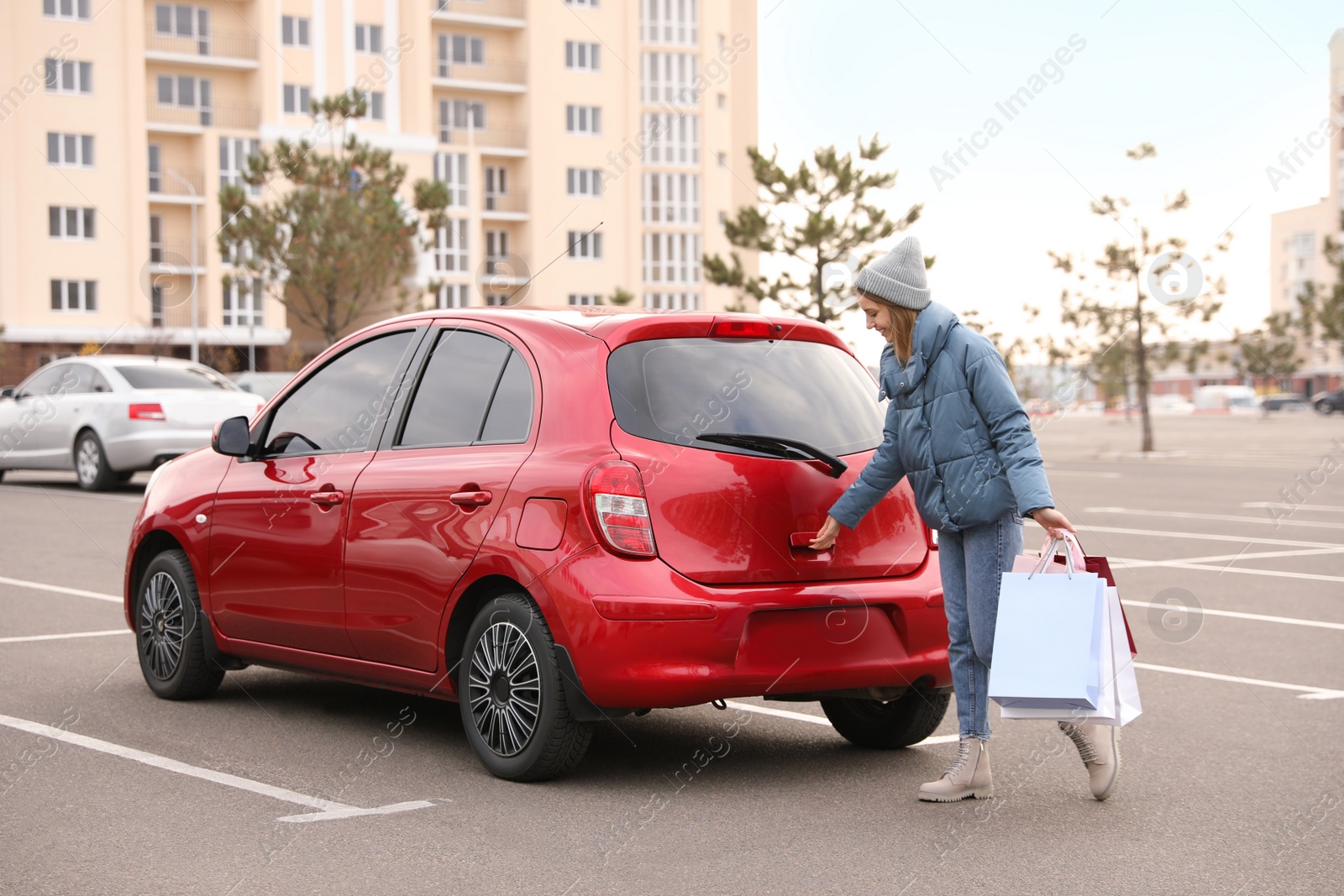 Photo of Woman with shopping bags near her car outdoors