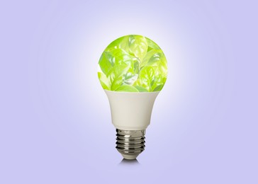 Image of Saving energy, eco-friendly lifestyle. Fresh green leaves inside of light bulb on lilac background