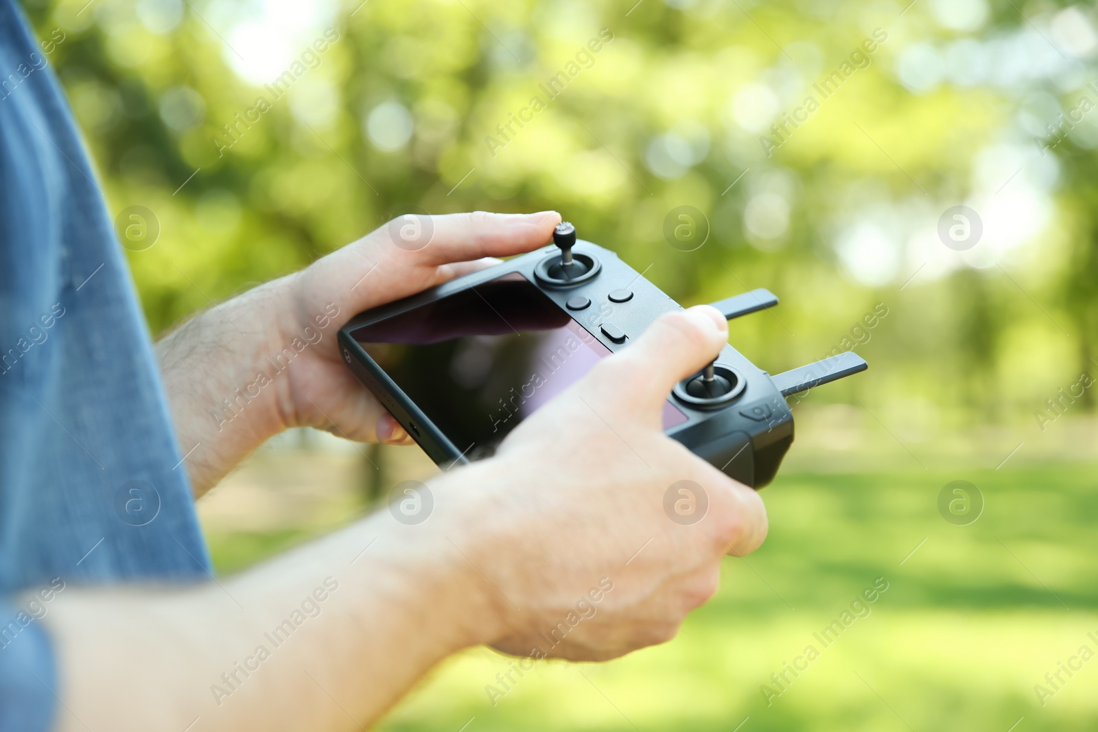 Photo of Man holding new modern drone controller outdoors, closeup of hands