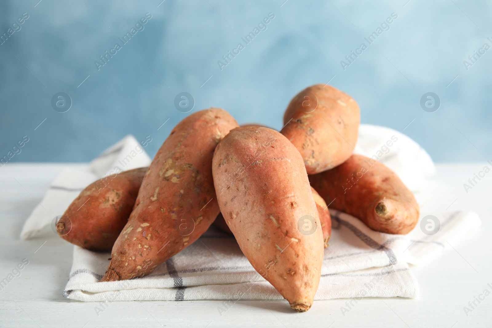 Photo of Sweet potatoes on table against color background