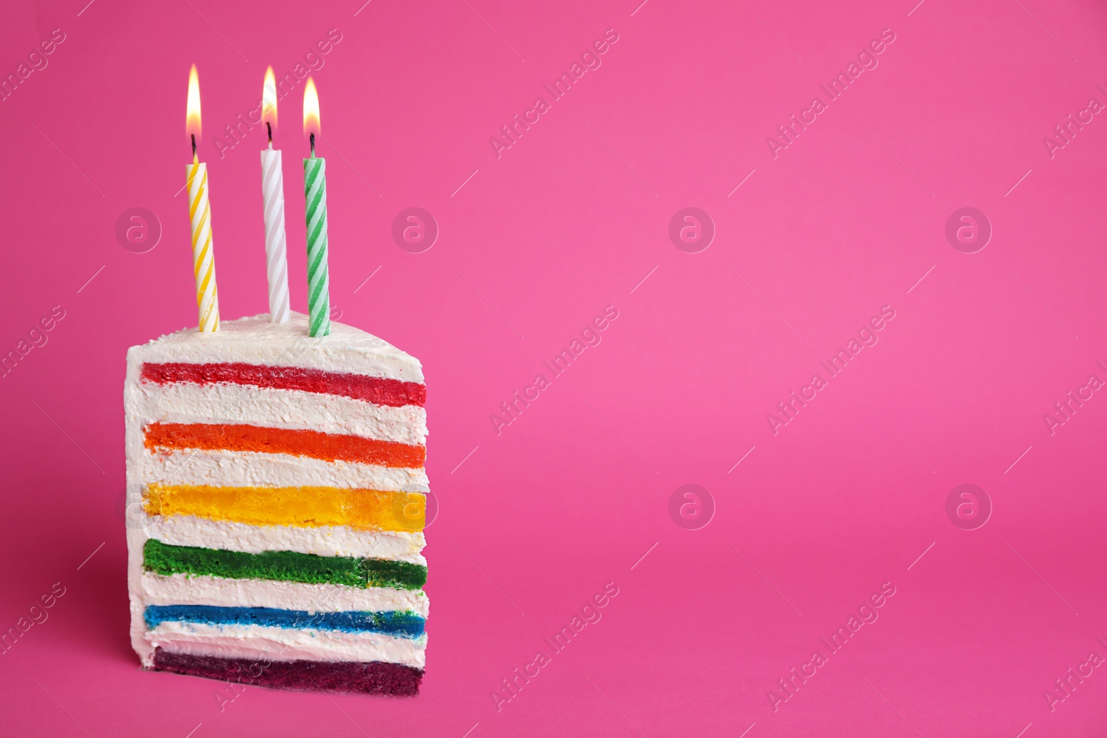 Photo of Slice of delicious rainbow cake with candles on color background