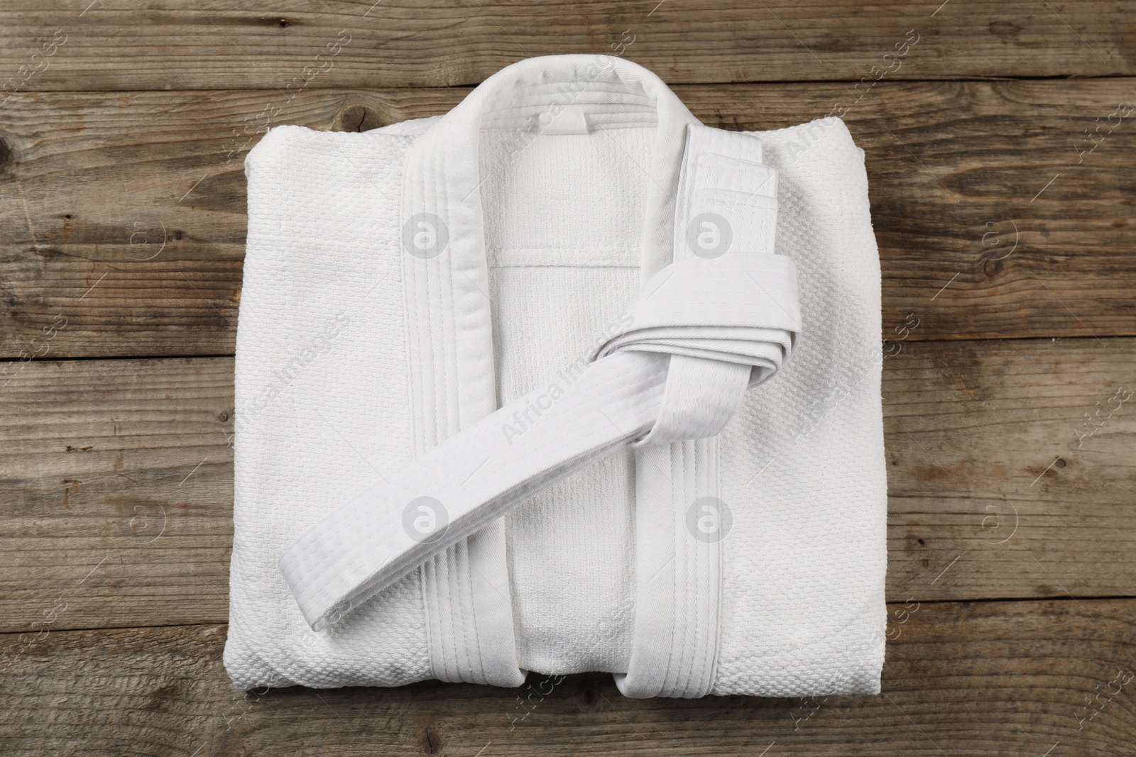 Photo of White karate belt and kimono on wooden background