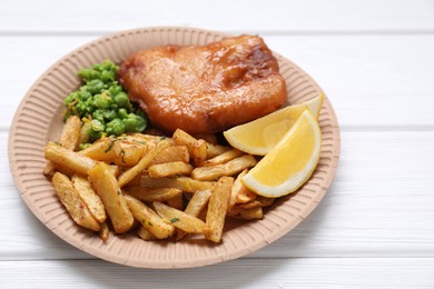 Photo of Tasty fish, chips, peas and lemon on white wooden table, closeup