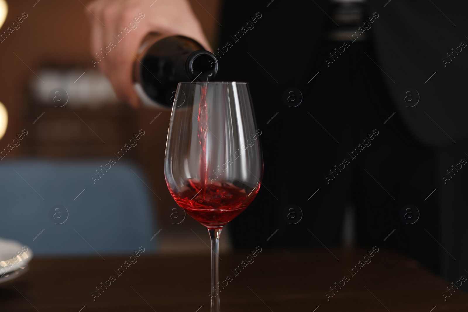 Photo of Man pouring wine into glass on table