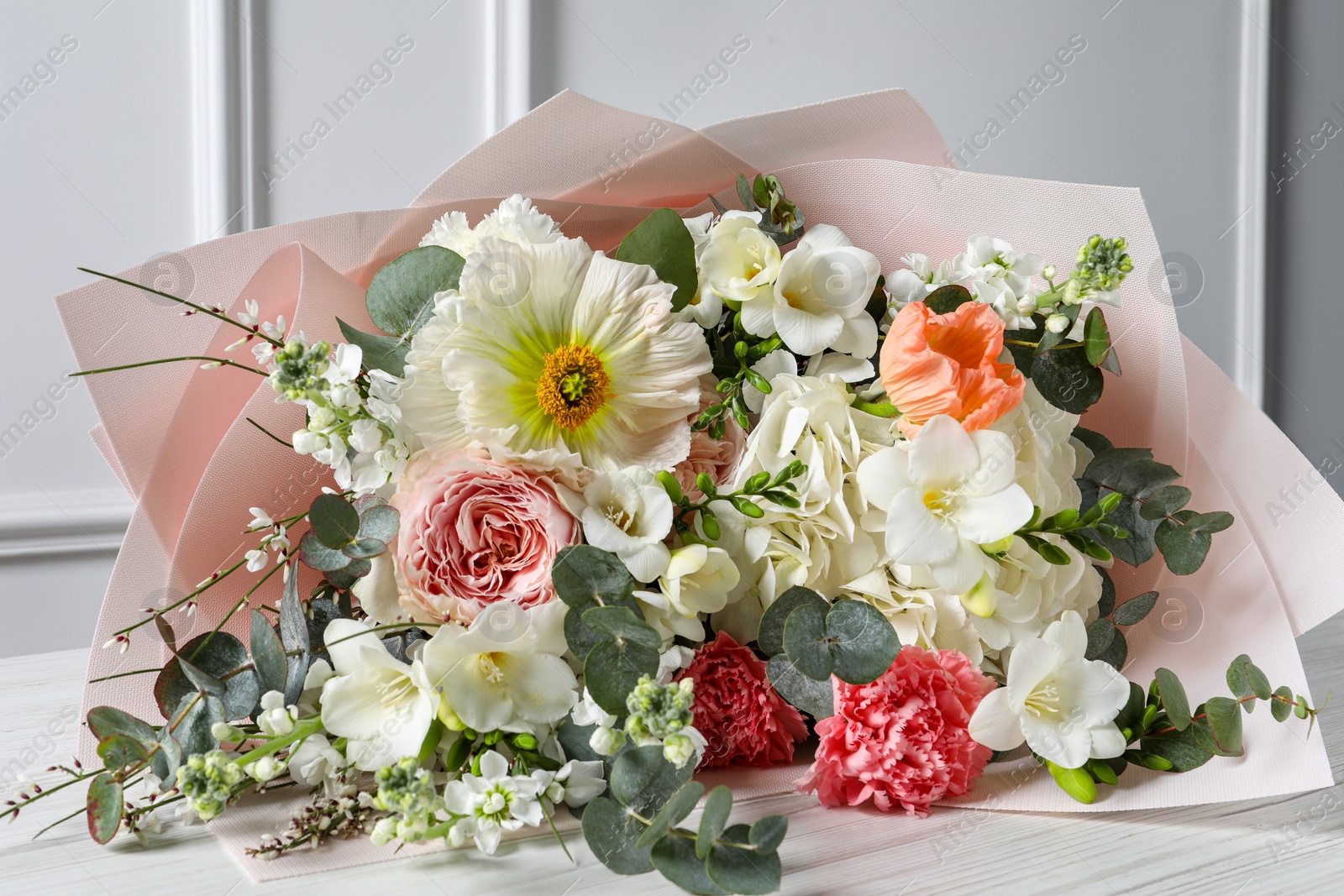 Photo of Bouquet of beautiful flowers on white wooden table, closeup