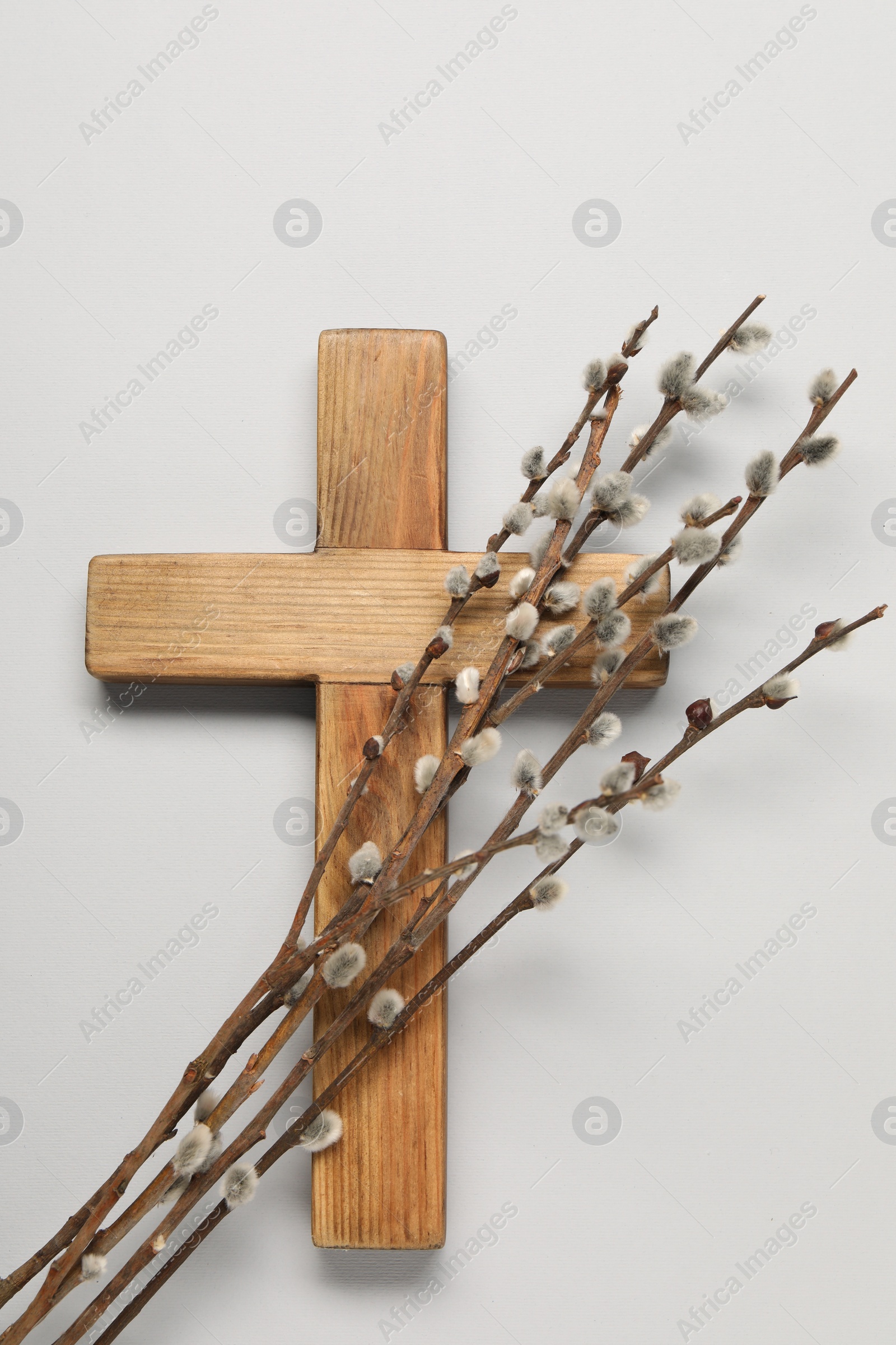 Photo of Wooden cross and willow branches on light grey background, top view. Easter attributes