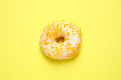 Photo of Delicious glazed donut on yellow background, top view