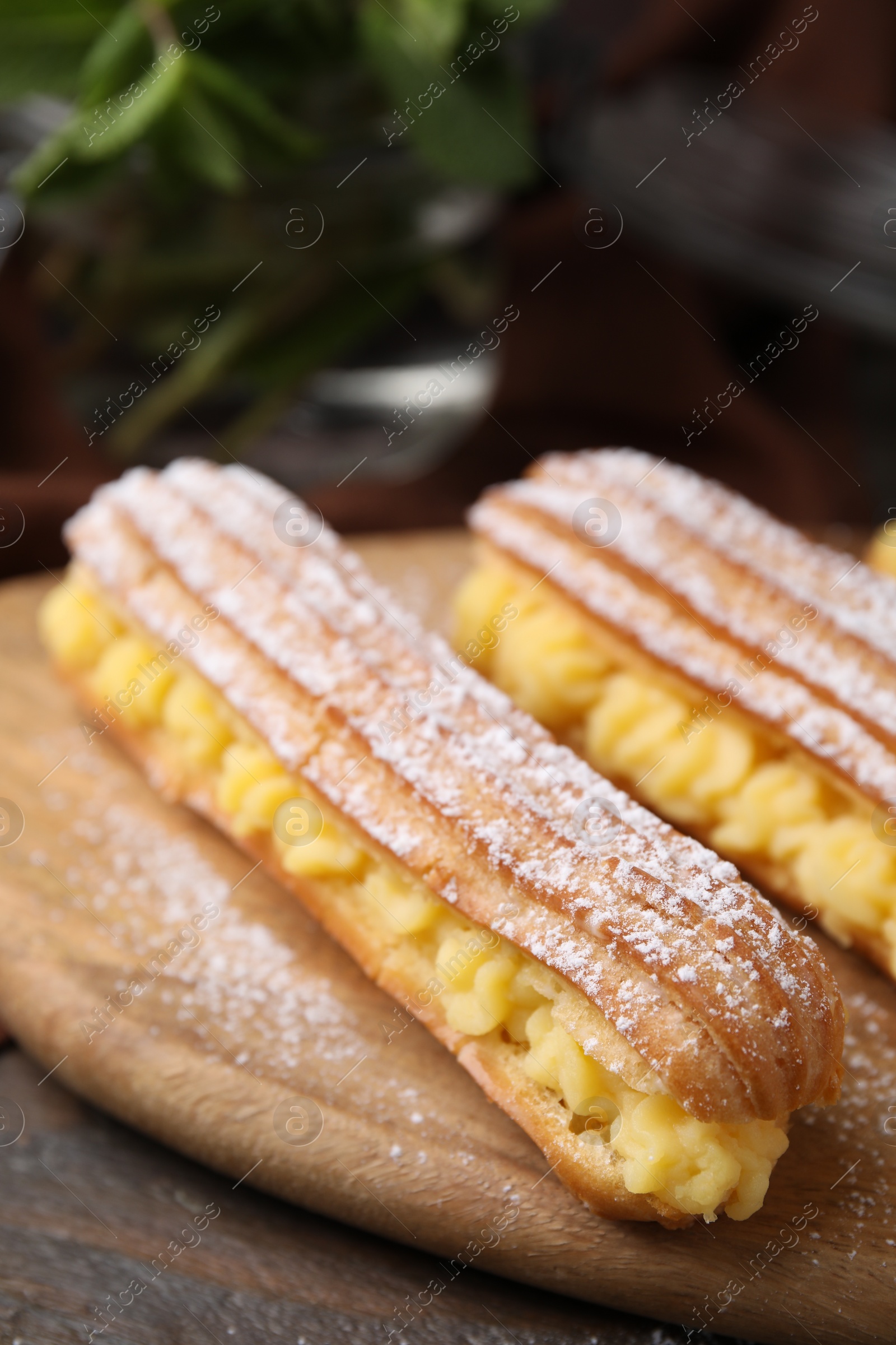 Photo of Delicious eclairs filled with cream on wooden table