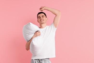 Photo of Happy man in pyjama holding pillow on pink background