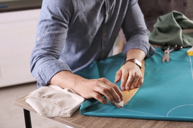 Tailor working with cloth at table in atelier