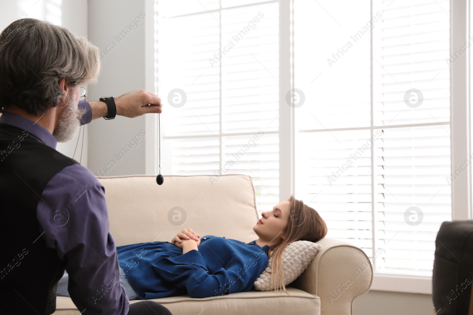 Photo of Psychotherapist using pendulum during hypnotherapy   session in office