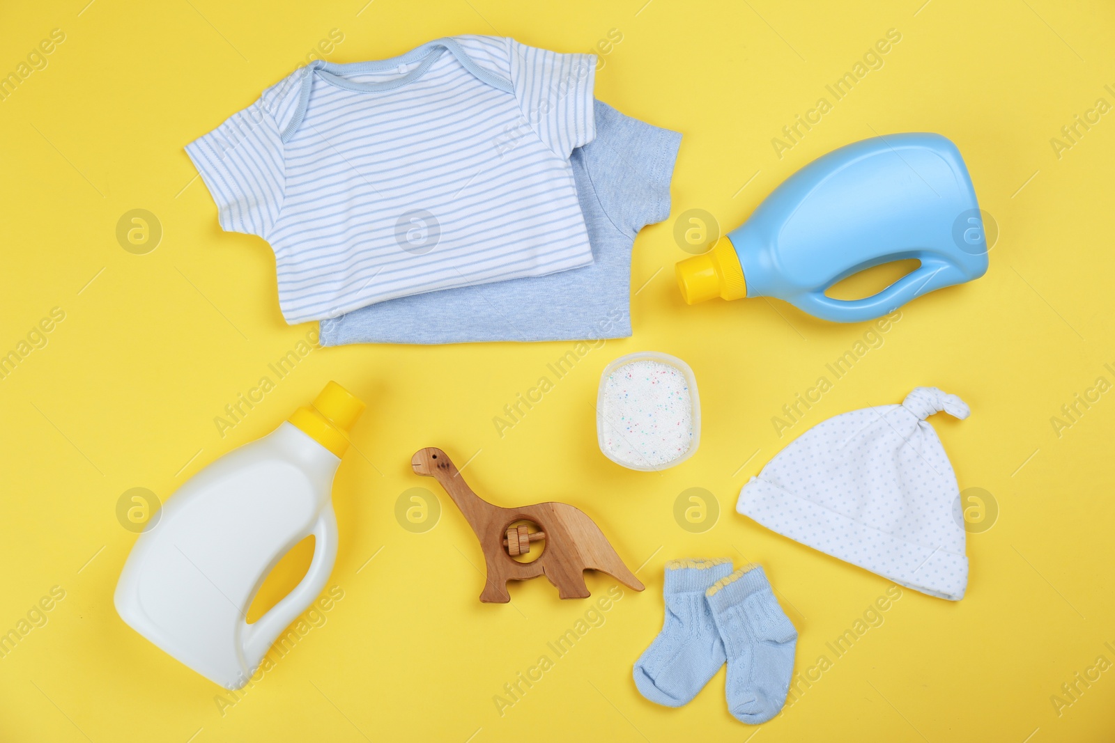 Photo of Flat lay composition with detergents and children's clothes on yellow background