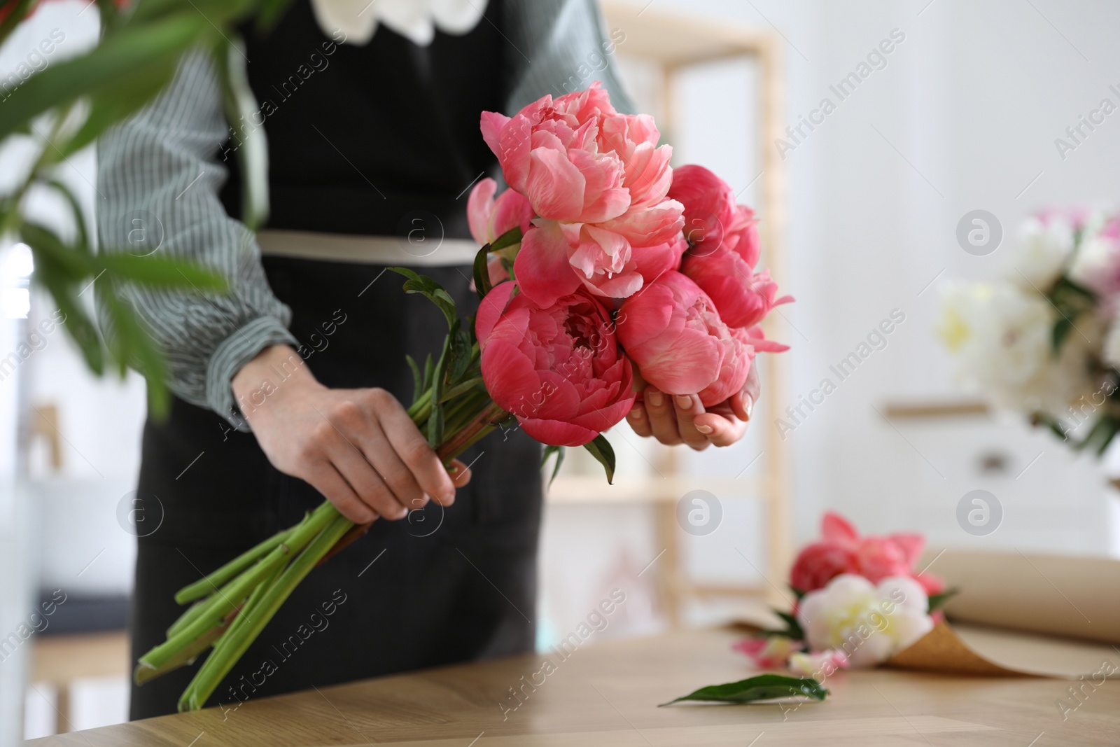 Photo of Florist making beautiful peony bouquet at table, closeup