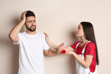 Young man rejecting engagement ring from girlfriend on beige background