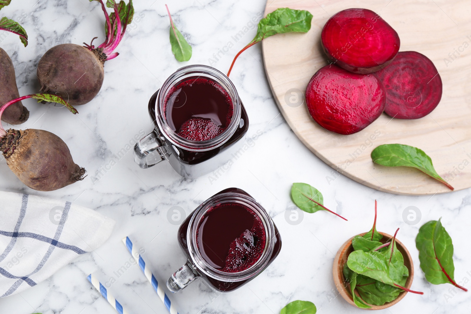 Photo of Freshly made beet juice on white marble table, flat lay