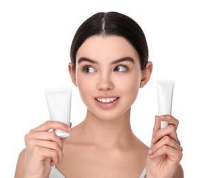 Photo of Teenage girl holding tubes of foundation on white background