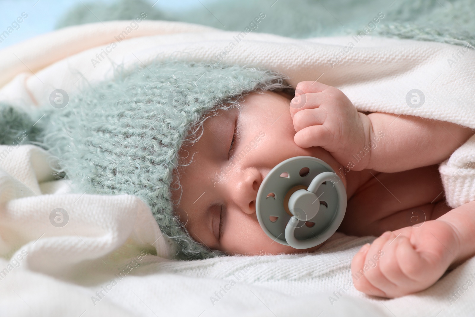 Photo of Cute newborn baby with pacifier sleeping on white blanket, closeup