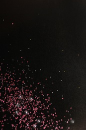 Photo of Rose gold glitter on black background, top view with space for text