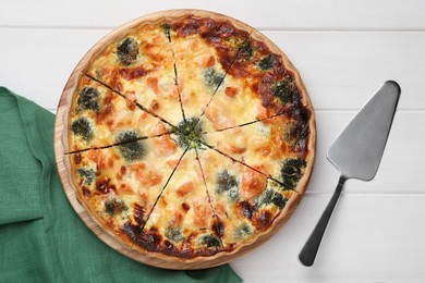 Photo of Delicious homemade salmon quiche with broccoli and spatula on white wooden table, flat lay