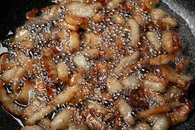 Photo of Frying cracklings in cookware, closeup. Pork lard