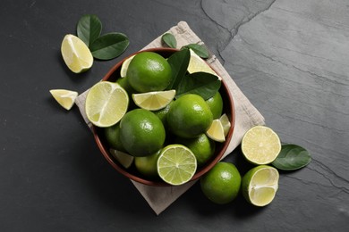 Fresh ripe limes in bowl on black table, top view