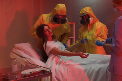 Photo of Professional paramedics examining patient with virus in quarantine ward