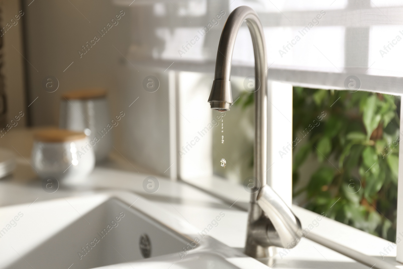 Photo of Water drops falling down from tap in kitchen
