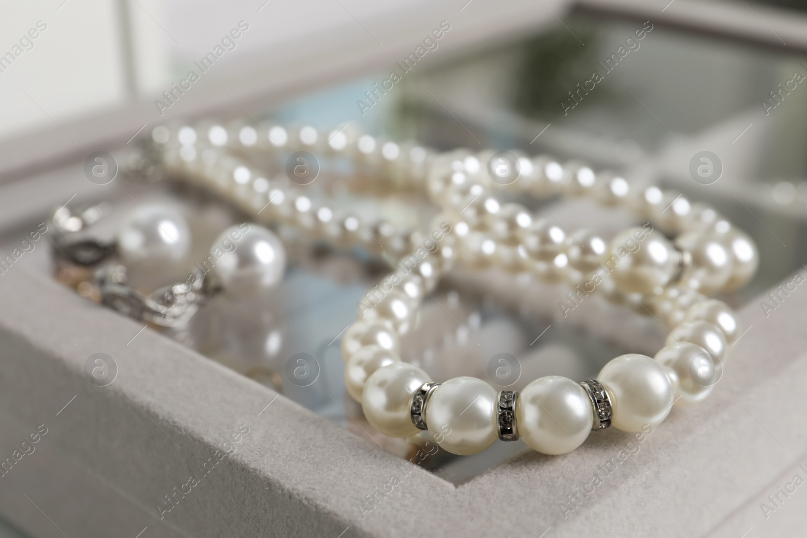 Photo of Luxurious pearl necklace and earrings on jewelry box, closeup