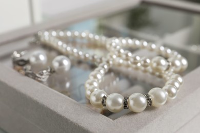 Luxurious pearl necklace and earrings on jewelry box, closeup