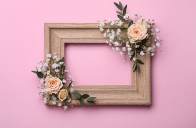 Wooden frame with gypsophila flowers, eucalyptus and roses on pink background. Space for text