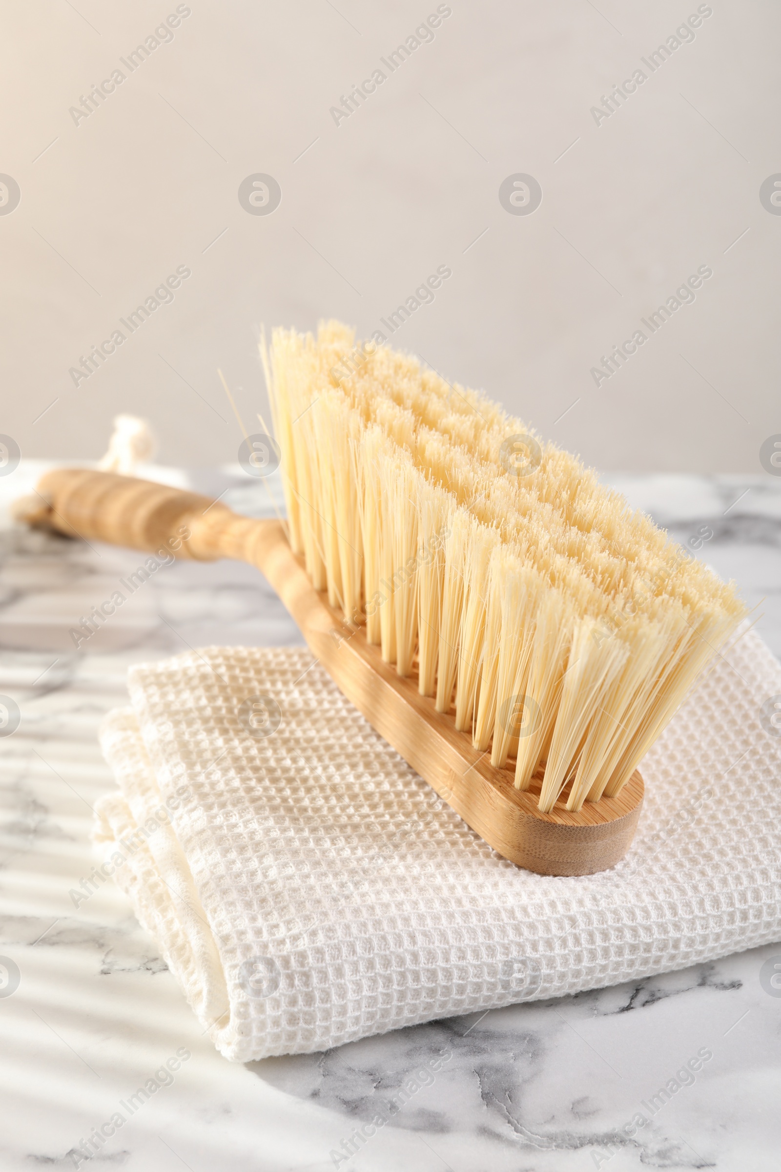 Photo of One cleaning brush and rag on white marble table, closeup