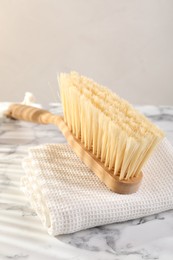 Photo of One cleaning brush and rag on white marble table, closeup