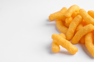 Photo of Heap of tasty cheesy corn puffs on white background, space for text
