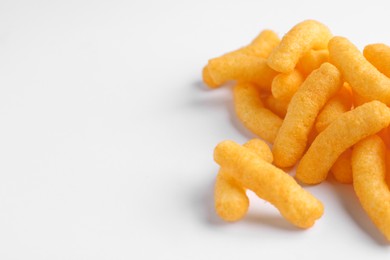 Heap of tasty cheesy corn puffs on white background, space for text